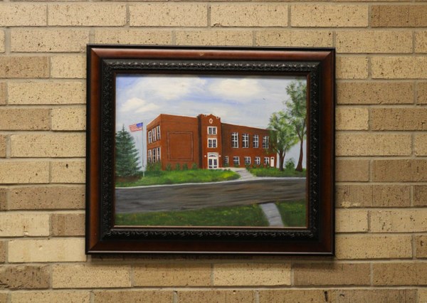 A painting of the old high school hung on a brick wall