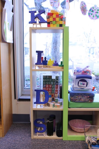 Part of a modern looking wood shelf holding toys in the kids' section